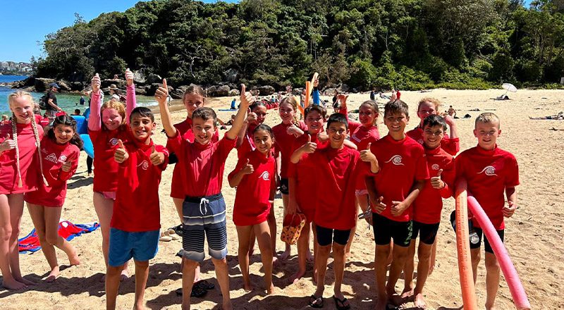 Students in red rashshirts on a beach from St Madeleine's Catholic Primary School Kenthurst