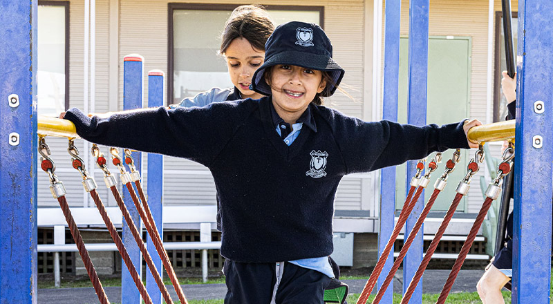Smiling child on play equipment at St Madeleine's Catholic Primary School Kenthurst